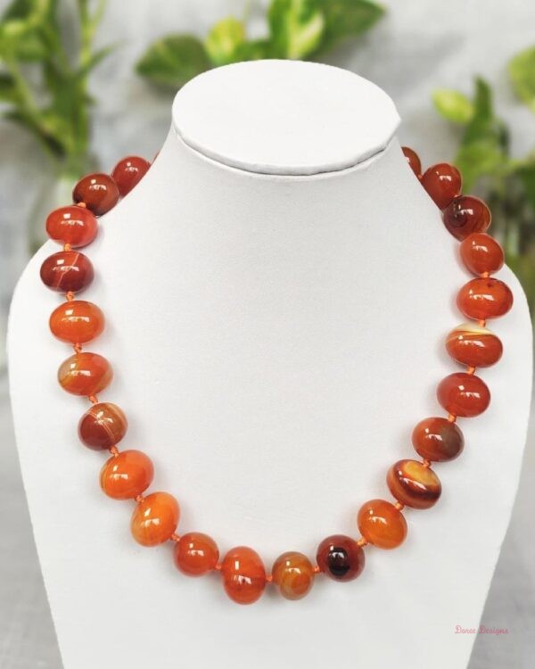 Translucent shades of ovoid-shaped toffee orange and burnt sienna coloured Onyx tumbles come together in this knotted 19” single strand necklace, with a strong spring-ring clasp for durability. DN 0002