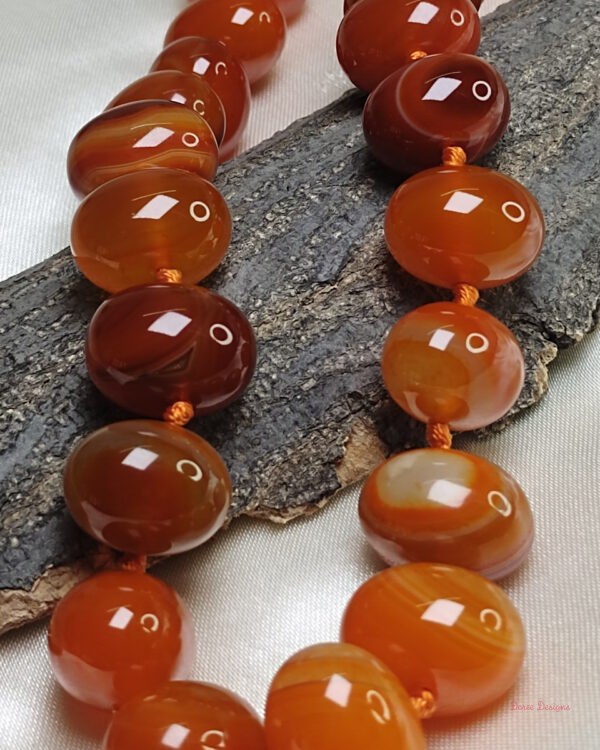 Translucent shades of ovoid-shaped toffee orange and burnt sienna coloured Onyx tumbles come together in this knotted 19” single strand necklace, with a strong spring-ring clasp for durability. DN 0002