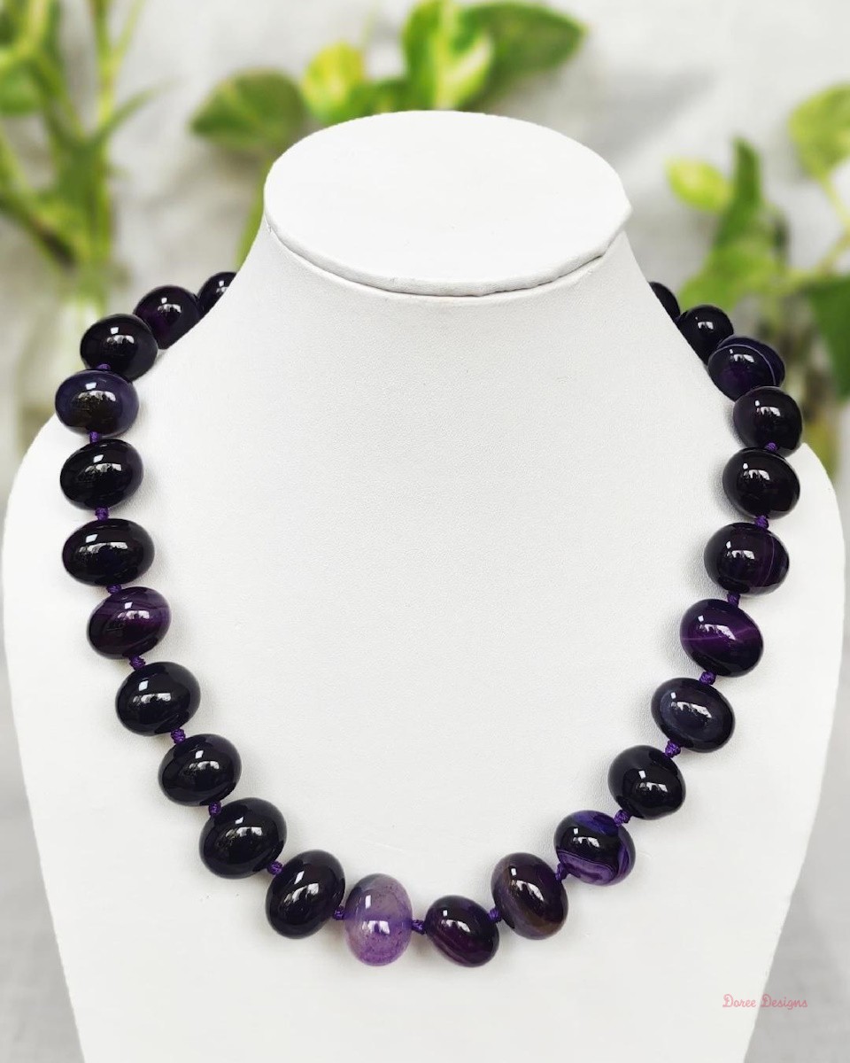 Deep and dark shades of ovoid-shaped deep indigo coloured Onyx tumbles come together in this knotted 19” single strand necklace, with a strong spring-ring clasp for durability. DN0010