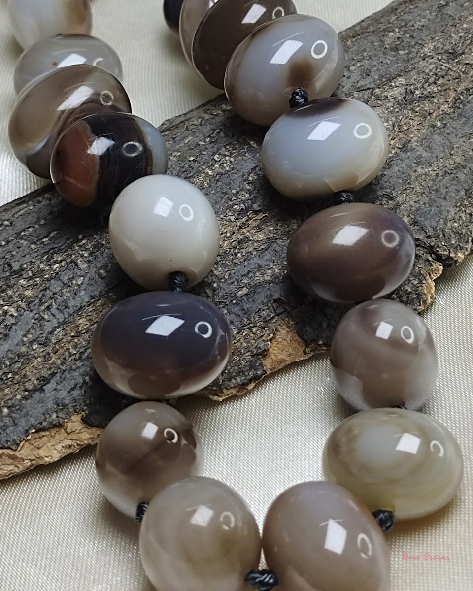 Delightful shades of ovoid-shaped white and brown chocolate coloured swirls of Onyx tumbles come together in this knotted 19” single strand necklace, with a strong spring-ring clasp for durability. DN0011